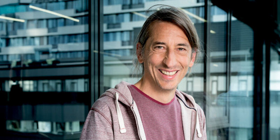 Photo: A portrait of Prof. Eike Kitz, a scientist with long hair and a purple sweater.