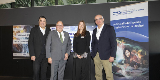 Vier MEnschen stehen vor einem Poster