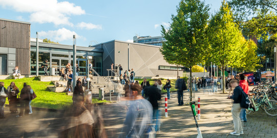 Students in summer in front of the University of Duisburg-Essen's lecture theatre centre on the Duisburg campus.