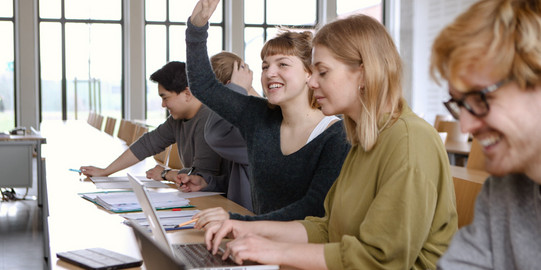 Lecture theatre with students, one of whom comes forward.