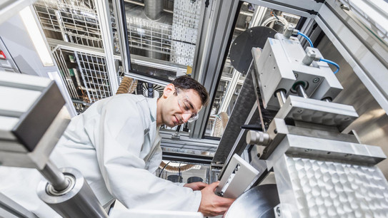 Ein Mann in einem Laboranzug bringt in einem Industrielabor eine Leiste an einer Maschine an