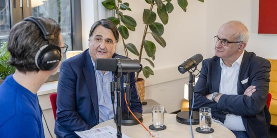 Drei Personen sitzen an einem runden Tisch.