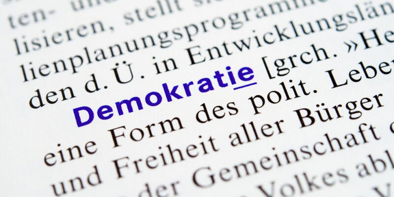 Book page with text; the word “democracy” is highlighted in blue.
