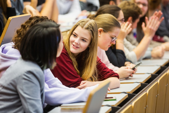 Young students, mainly women, chat in a lecture theatre at the University of Duisburg-Essen.