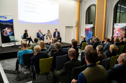 Foto: Ein Publikum schaut auf eine hell erleuchtete Bühne, auf der Prof. Barbara Albert, Rektorin der Universität Duisburg-Essen, Prof. Martin Paul, Rektor der Ruhr-Universität Bochum und Prof. Manfred Bayer, Rektor der Technischen Universität Dortmund, miteinander sprechen.