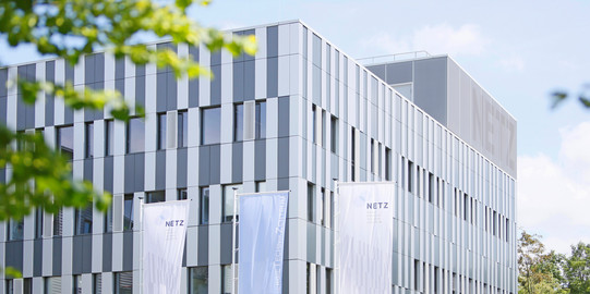 View of the facade of the NETZ research building with flags of the institutes located in the foreground on the Duisburg campus of the University of Duisburg-Essen.